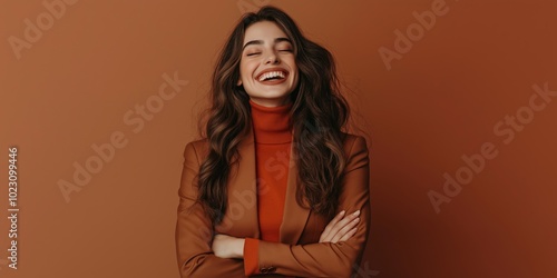 A woman with long hair is smiling and wearing a brown jacket. She is posing for a picture and she is happy