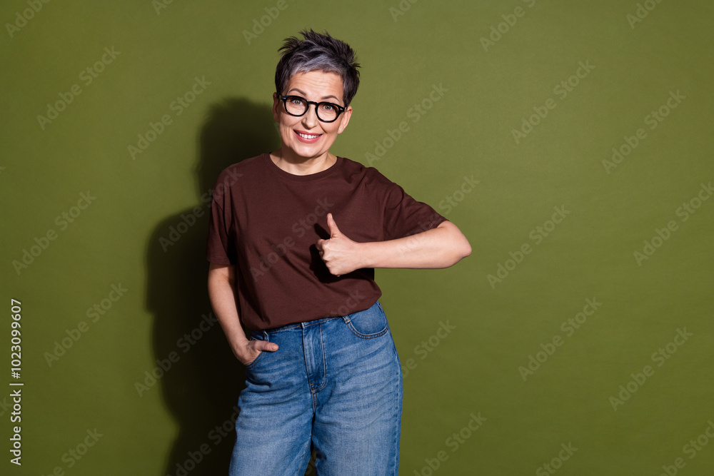 Portrait of pretty aged lady thumb up empty space wear brown t-shirt isolated on khaki color background Portrait of pretty aged lady thumb up empty space wear brown t-shirt isolated on khaki color background