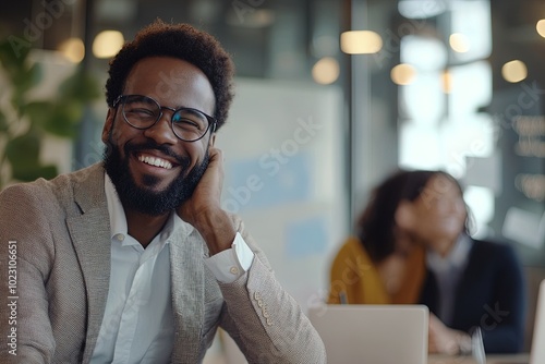 Smiling Man in a Suit Enjoying a Light Moment at a Modern Office During a Team Discussion