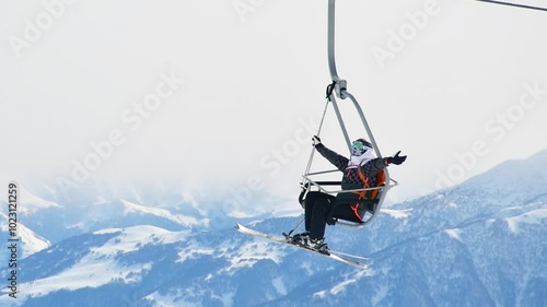 Georgia, 2022 : happy skier wear mask sit on chairlift enjoy views pose outstretch arms on winter ski holidays outdoors. Xmas holidays and fun in mountains photo