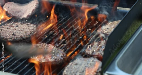 flipping burgers on backyard grill, with open flame