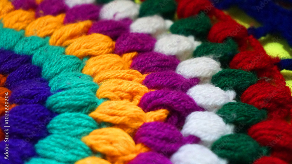 A Piece of knitting with color threads ball of yarn and a knitting needle on red background. A Piece of knitting with color threads ball of yarn and a knitting needle on red background.