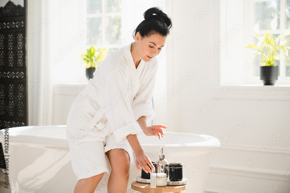 Beautiful middle-aged mature caucasian woman in spa bathrobe using applying beauty products jars for skin care, rejuvenation, softening effect while taking bath shower at home Beautiful middle-aged mature caucasian woman in spa bathrobe using applying beauty products jars for skin care, rejuvenation, softening effect while taking bath shower at home