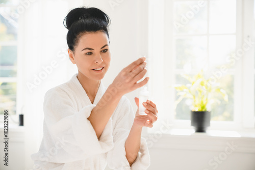 Closeup cropped portrait of caucasian middle-aged mature woman in spa bathrobe using rejuvenation serum for skin care after taking shower bath at home. Beauty procedures concept