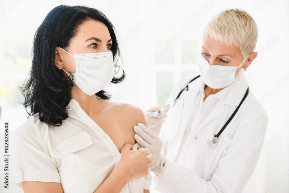 Vaccination concept. Doctor giving an injection to mature female patient in clinic. Coronavirus Covid 19 vaccine. Doctor making an injection with a syringe Vaccination concept. Doctor giving an injection to mature female patient in clinic. Coronavirus Covid 19 vaccine. Doctor making an injection with a syringe