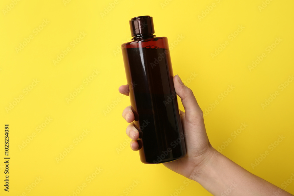 Woman with shampoo bottle on yellow background, closeup Woman with shampoo bottle on yellow background, closeup