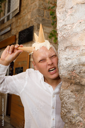 Bald man with ice cream on his head, on an old street in Italy, Montenegro, Croatia.