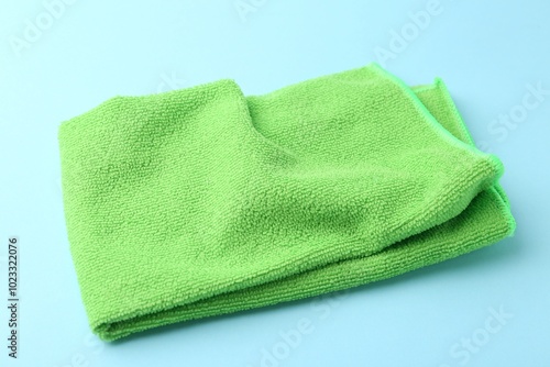 Clean green microfiber cloth on light blue background, closeup