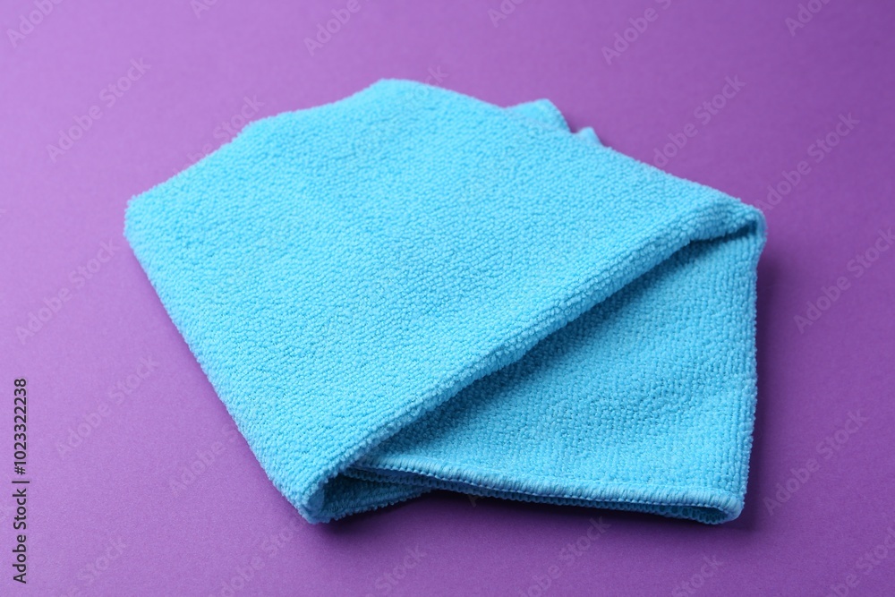 Clean light blue microfiber cloth on purple background, closeup Clean light blue microfiber cloth on purple background, closeup