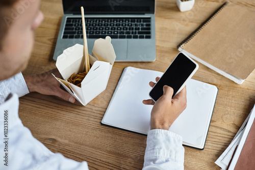 A businessman in a white shirt multitasks by reviewing a project and enjoying noodles in a modern workspace. photo