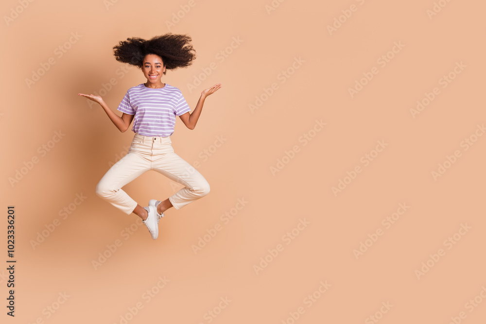 Full length portrait of pretty young woman jump hold empty space wear t-shirt isolated on beige color background Full length portrait of pretty young woman jump hold empty space wear t-shirt isolated on beige color background