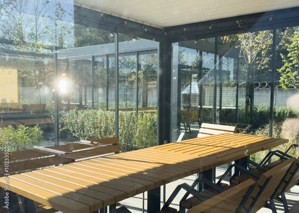 Fototapeta premium A spacious barbecue area with a canopy made from natural materials, enclosed. A patio with a table and chairs, sitting under a roofed structure.