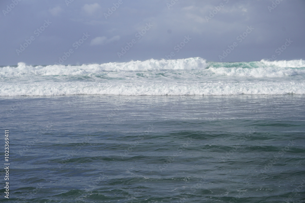 Ocean waves crashing on the shore, with calm water in the foreground Ocean waves crashing on the shore, with calm water in the foreground