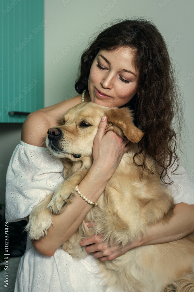 Portrait of a happy young woman and her dog sitting together at home. Golden retriever and owner