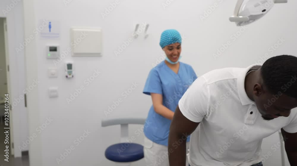 A dental hygienist and an African male patient enter the treatment room for a consultation in a modern clinic. Concept of personalized patient care and professionalism. A dental hygienist and an African male patient enter the treatment room for a consultation in a modern clinic. Concept of personalized patient care and professionalism.