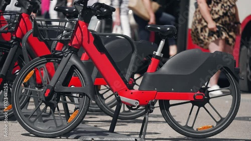 Electric bike at charging station, Electrical bicycles ready for sharing or rent. Paying for use green cycling. Eco friendly urban healthy transport. Red modern bike
