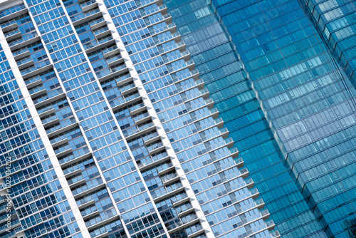 A series of modern skyscrapers with glass façades create a geometric pattern. The buildings reflect the sky, enhancing the sleek, urban aesthetic.