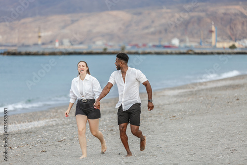 Happy couple walking hand in hand along Playa del Zapillo's sandy beach in Almeria, Spain on a sunny day