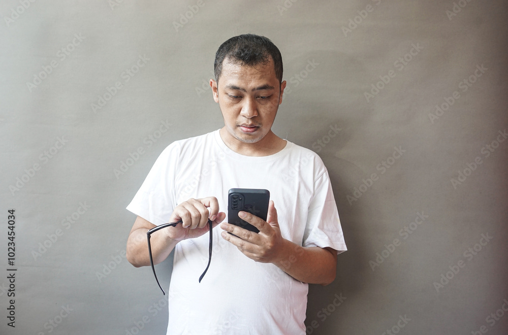 Fototapeta premium Man Using Smartphone, Concentrated Expression, Casual Attire
