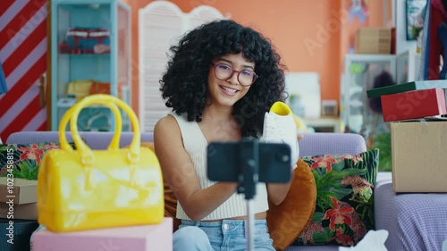 Young woman selling clothes and accessories online from home. Fashionable girl owning a small online business in her colored apartment. 