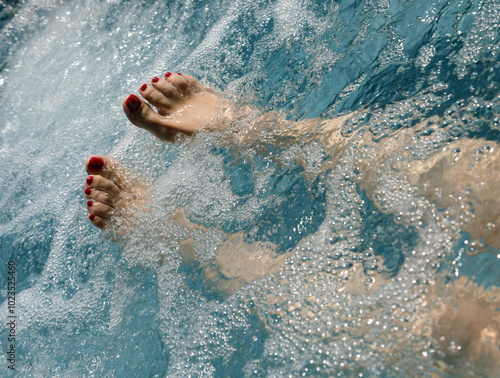 Photography feet with red nail polish of a woman during hydrotherapy to stimulate blood circ