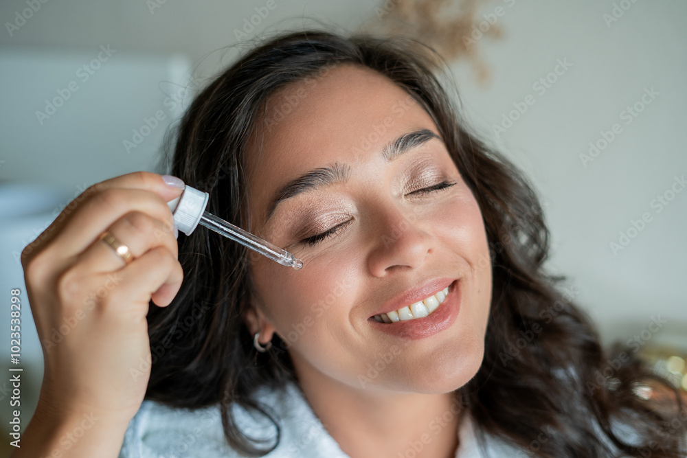 Young, beautiful, dark haired woman of 39 years applies rejuvenating serum to her face. Home spa. Healthy skin care. Young, beautiful, dark haired woman of 39 years applies rejuvenating serum to her face. Home spa. Healthy skin care.