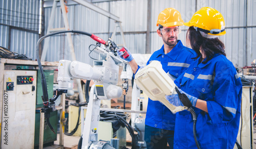 Engineers team mechanic using computer controller Robotic arm for welding steel in steel factory workshop. Industry robot programming software for automated manufacturing technology