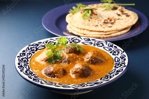 Malai Kofta Curry is an indian cuisine dish with vegetables & cottage cheese fried balls in onion tomato gravy with spices served in ceramic bowl 