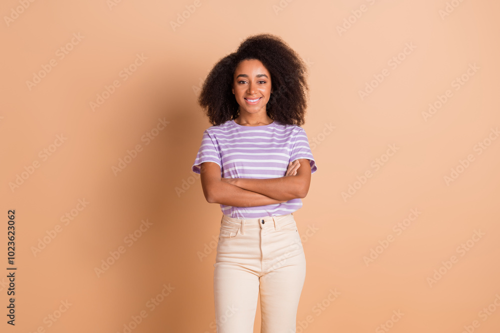 Portrait of pretty young woman folded arms wear striped t-shirt isolated on beige color background Portrait of pretty young woman folded arms wear striped t-shirt isolated on beige color background