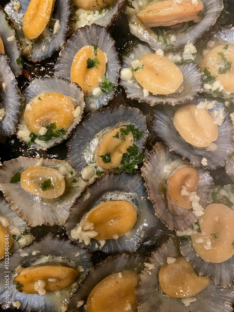 Grilled limpets, a traditional Azorean dish, served with fresh lemon and herbs. A delightful taste of the sea, showcasing the region's rich culinary heritage. Grilled limpets, a traditional Azorean dish, served with fresh lemon and herbs. A delightful taste of the sea, showcasing the region's rich culinary heritage.