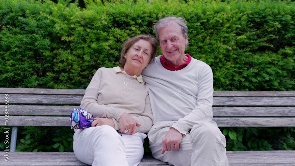 Older couple sitting closely on a park bench, leaning on each other with content smiles, embodying a moment of peaceful companionship and enduring love Older couple sitting closely on a park bench, leaning on each other with content smiles, embodying a moment of peaceful companionship and enduring love