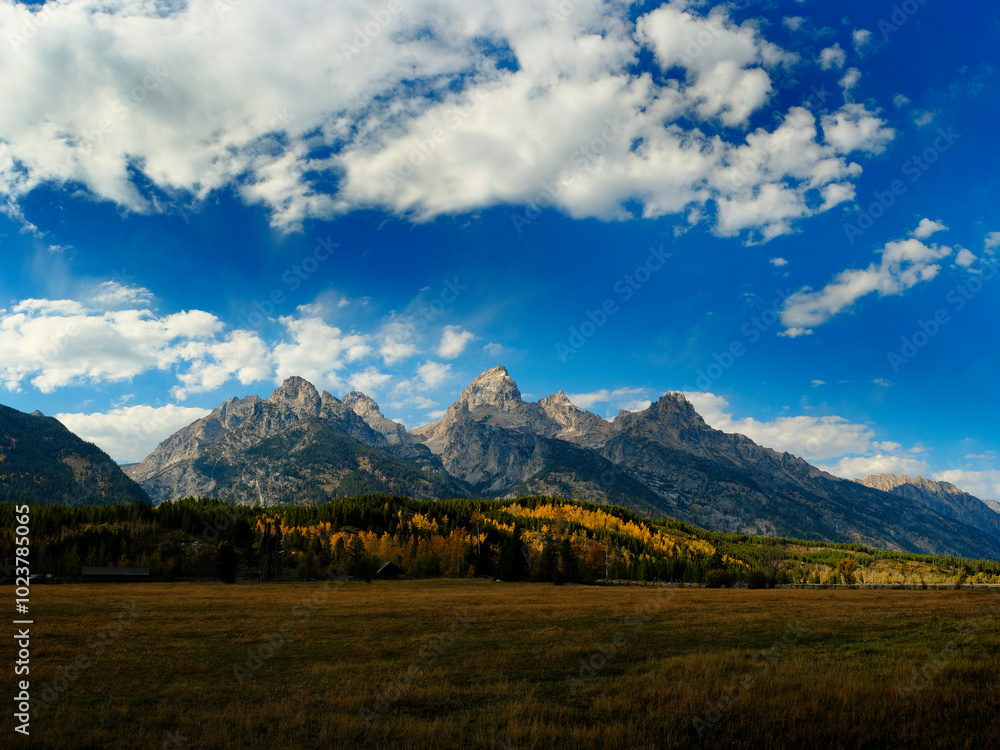 Grand Teton Mountains Tetons in Wyoming Rugged Mountain Range in Autumn Fall Landscape with blue sky and clouds Grand Teton Mountains Tetons in Wyoming Rugged Mountain Range in Autumn Fall Landscape with blue sky and clouds