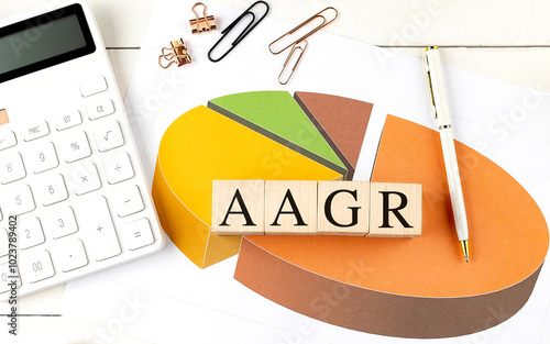 AAGR text on a wooden blocks with pie chart, calculator, and office supplies on desk photo