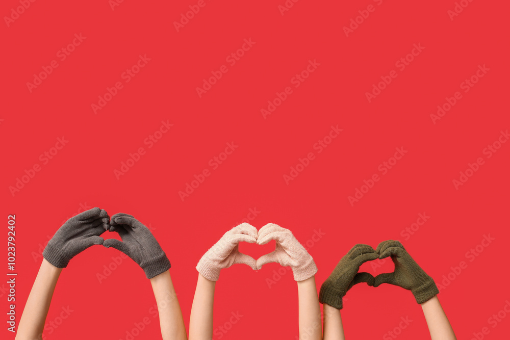 Hands in warm gloves making hearts on red background Hands in warm gloves making hearts on red background