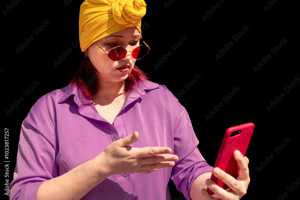 Happy and funny cool lady with fashionable clothes on dark background look to the phone with outrage- adult asian with extravagant style. isolated on black background