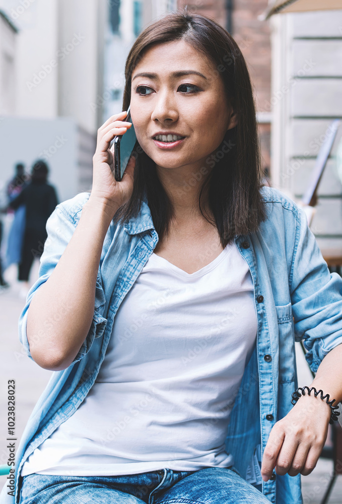 Attractive Asian woman dressed in casual denim outfit making international conversation with operator customer service for discussing details about account balance and roaming 4g connection Attractive Asian woman dressed in casual denim outfit making international conversation with operator customer service for discussing details about account balance and roaming 4g connection