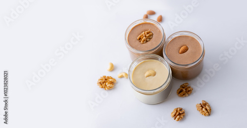 Three Urbech paste of almond, cashew, walnut nuts in glass jar on white background banner, top view photo