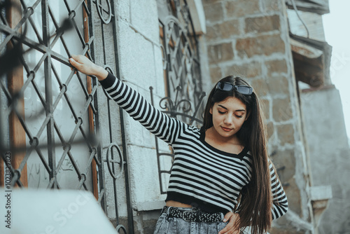 Stylish woman by metal fence in the city photo