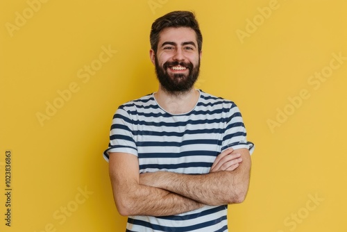 Smiling man in casual attire with crossed arms.