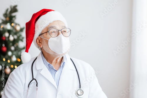 Senior doctor wearing a Santa hat and face mask, standing by Christmas decorations, symbolizing healthcare workers celebrating the holidays during pandemic times with festive cheer and safety measures photo