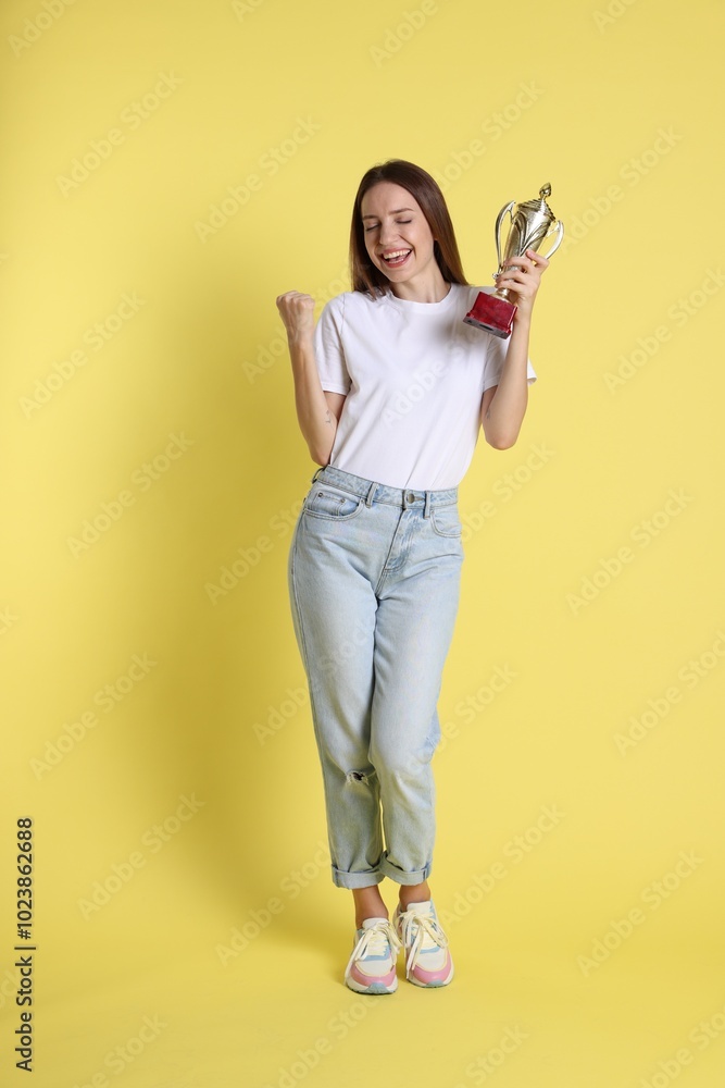 Happy winner with gold trophy cup on yellow background Happy winner with gold trophy cup on yellow background