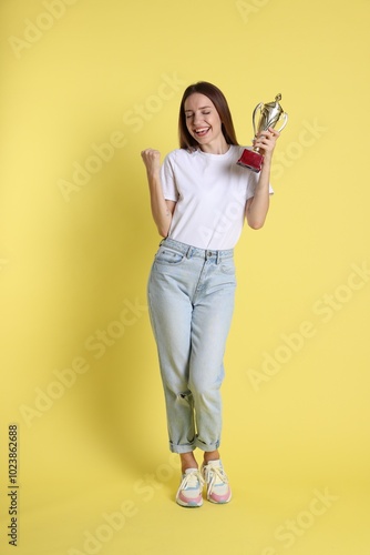 Happy winner with gold trophy cup on yellow background