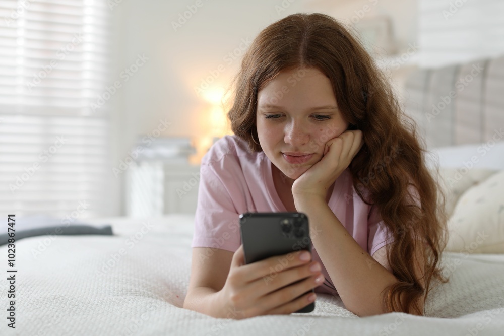 Beautiful teenage girl using smartphone on bed at home Beautiful teenage girl using smartphone on bed at home