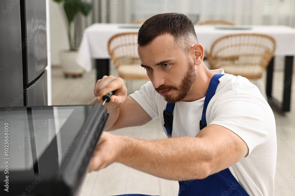 Fototapeta premium Repairman with screwdriver fixing oven at home