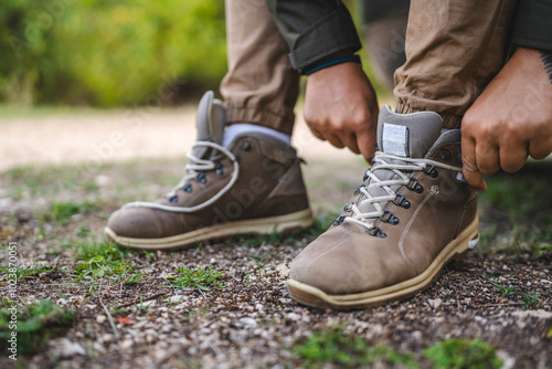 Man tying hiking boots on a grassy path in outdoor setting photo