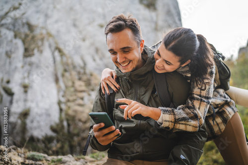 Girlfriend hug boyfriend while he use mobile phone on hiking