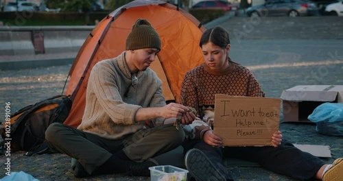 A homeless family collects alms. A homeless man is counting money in a sad way.