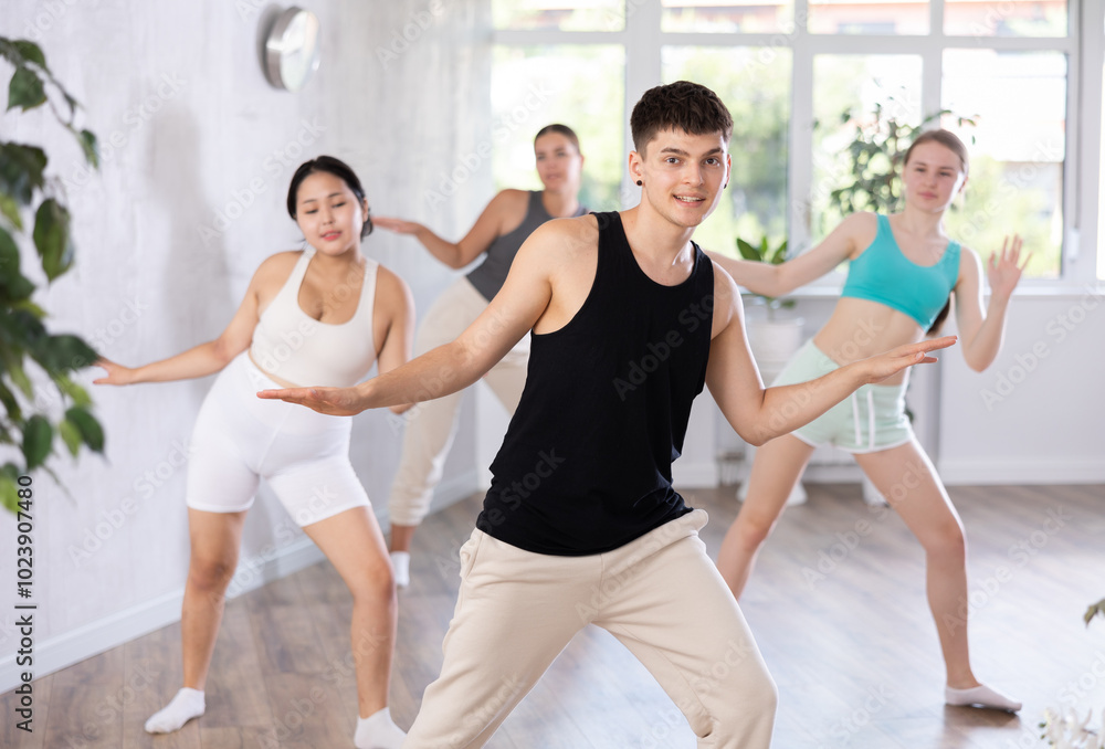Fototapeta premium Happy young women and man wearing sportswear smiling dancing in fitness studio in morning.