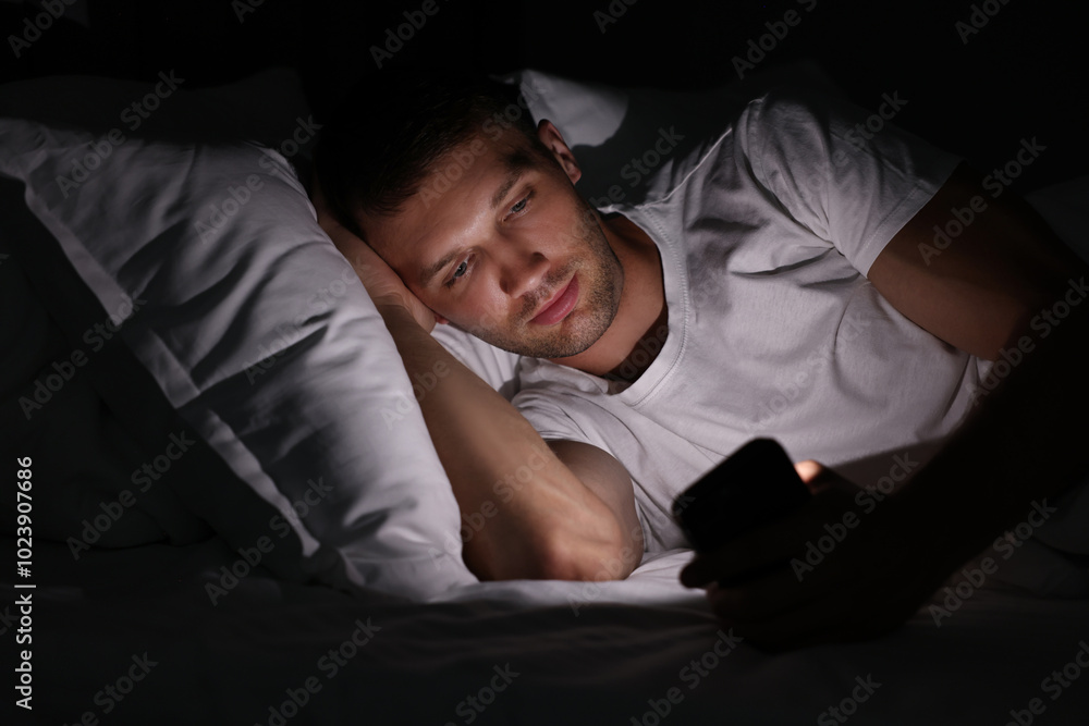 Bad habit. Man using smartphone in bed at night Bad habit. Man using smartphone in bed at night