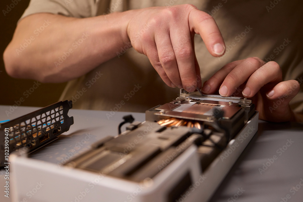 Fototapeta premium Hand Repairing a Graphics Card through the Application of Thermal Paste for Better Performance